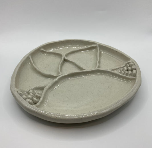 A round ceramic divided serving platter with organic leaf-like sections and textured grapevine details, shown on a neutral light gray background.